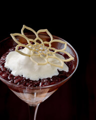 A dessert in a glass with a leafy design on top. The dessert is a combination of rice pudding and whipped cream. The glass is a martini glass, and the dessert is served in a martini glass