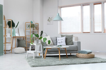 Interior of light living room with sofa, table and blinds on window