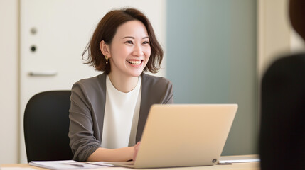 Naklejka premium Young businesswoman smiling and working on laptop in office meeting