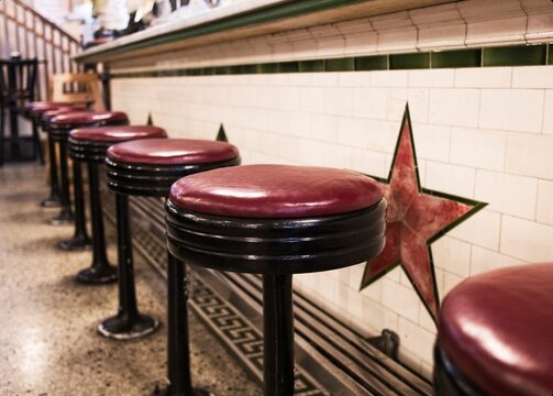 Old-fashioned, round, soft-covered stools at a vintage drug store soda fountain counter.