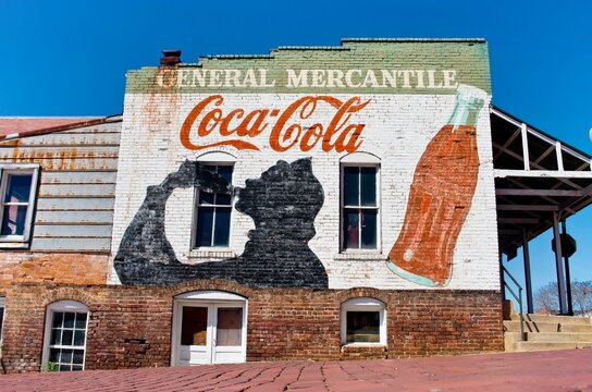 Old brick retail store with colorful Coca-Cola advertisement painted on the building.