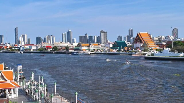 View of the River, where boats can be seen sailing on the water, buildings in Bangkok, and Wat Arun a landmark of Thailand. 