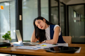 A woman is sitting at a desk with a laptop and papers