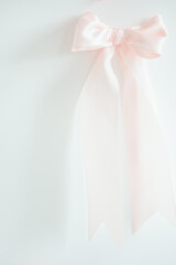 Soft pink modern satin bow on a bright white background with copy space
