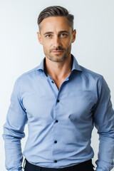 Portrait of a Man in His Early 40s:  Close-up of a Confident Male Wearing a Crisp Light Blue Button-Down Shirt and Jeans, Displaying a Well-Groomed Appearance with Short, Dark Hair and a Slightly