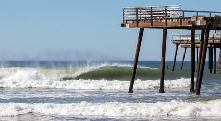 Dilapidated Pier and Surfer