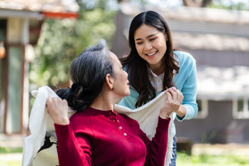Asian senior woman in wheelchair with happy daughter. Family relationship retired woman sitting on wheelchair in the park age care at retirement home.
