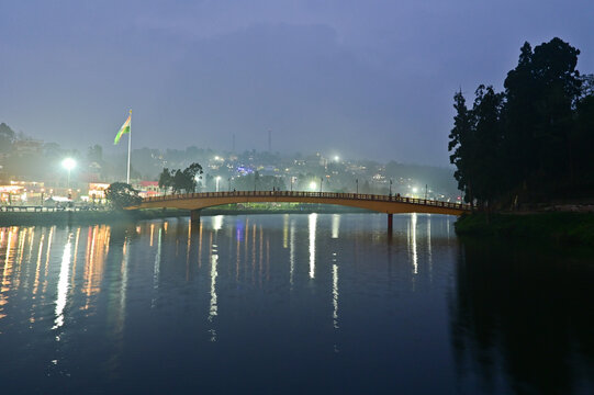 The night view of Mirik Lake is a serene and enchanting sight. Soft lights reflect gently off the calm water, creating a shimmering mirror-like surface. 