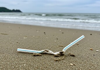 A close-up of a plastic straw discarded on the beach