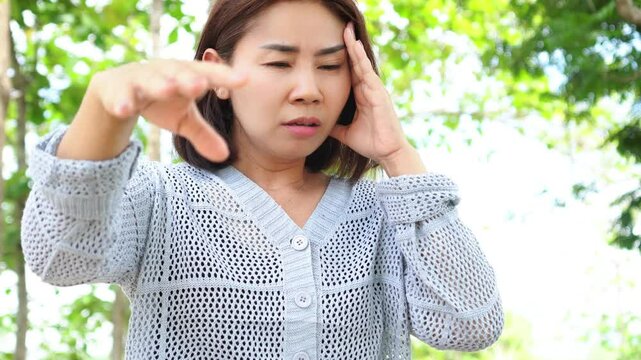 asian woman suffering from anemia, feeling faint and dizzy with vertigo and signs of syncope while walking outdoors, caused by low oxygen levels and poor blood circulation
