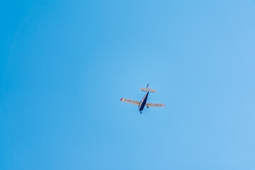 Small ultralight airplane with overhead wing and single propeller flying in sunset sky.