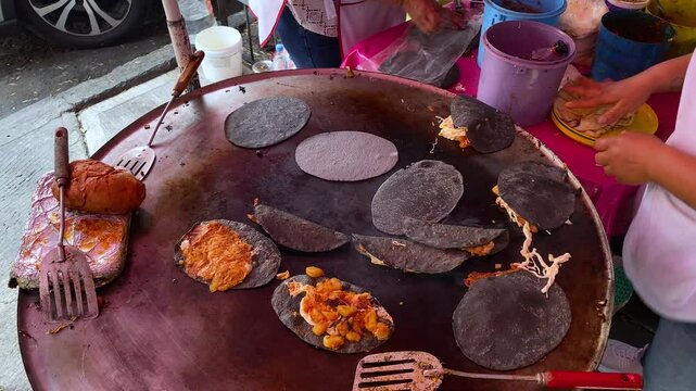 Street food vendor prepares Quesadillas and Tlacoyos made with fresh blue corn tortillas in Mexico City, Mexico.