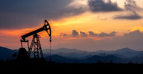 Oil pumpjack working with silhouette against a vibrant sunset sky. Industrial machine extraction energy from earth. Stock market investment and business concept.