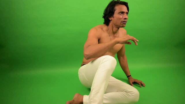 Shirtless man sits shielding himself fearfully