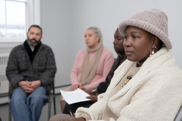 Obraz premium In the large white room, there is a circle of people sitting on chairs in different poses and positions for a group therapy or support meeting. 