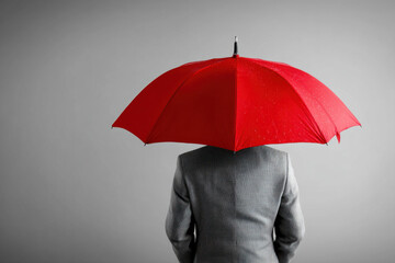 Business Man Holding a Red Umbrella, a conceptual photo relating to business and protection