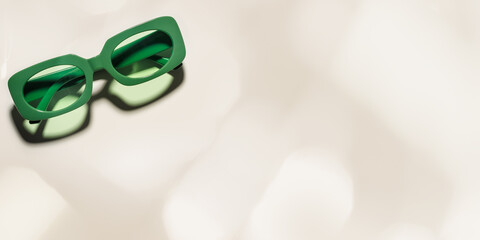 Stylish green colored sunglasses with sunshine on beige background, banner, shadow and glare from...