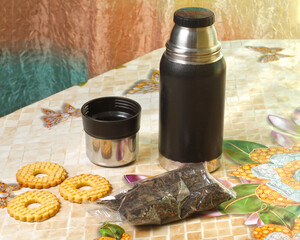 A thermos for tea on the table. Modern thermos on the kitchen table.