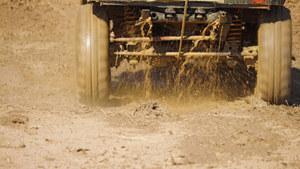 Off-road vehicle driving through mud. Close-up of the front wheels of an SUV driving through thick mud. Tires whip up the mud, creating splashes.