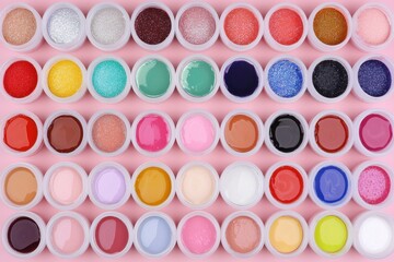 Colorful Collection of Nail Polish in Round Containers on Pink Background