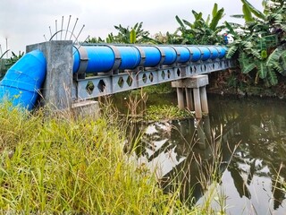 A large blue water steel pipe bridge river crossing, supported by concrete and steel frames, was...