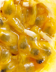 A close up of a yellow fruit with black seeds
