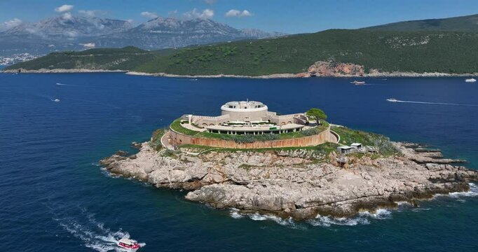 Mamula Island Hotel And Fortress On Rocky Islet In Boka Bay, Montenegro. Lush Green Hills And Mountains In Background. aerial pullback shot