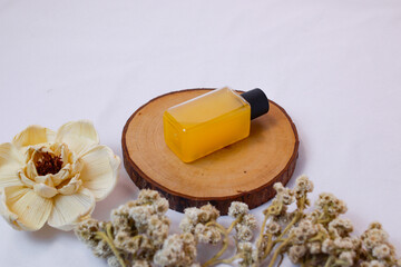 A minimalist product shot showcases a rectangular, transparent bottle filled with a vibrant yellow...