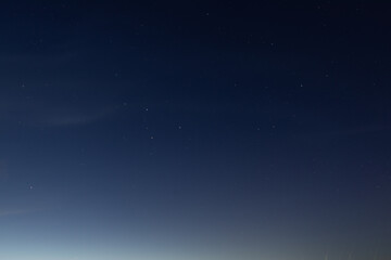A clear night sky filled with visible stars gradually fades into a soft horizon glow, creating a tranquil and minimal celestial scene copy space present.