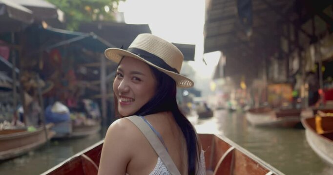 Young Asian tourist woman cheerful and happy to sight seeing travel by boat along the canel at Damnoen Saduak Floating Market Thailand.