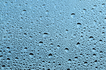 Water drops on the glass, blue sky texture background..Rain drops on window glass. Natural Pattern of raindrops.