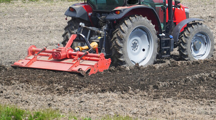 Obraz premium Tractor Cultivating Soil in an Agricultural Farm Field（畑の土を耕す耕運機（トラクター）） 