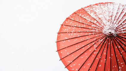 red umbrella is covered with delicate snowflakes against white background, creating striking contrast. scene evokes sense of calm and beauty in winter setting