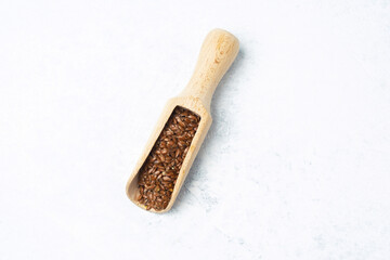 Wooden scoop filled with flax seeds resting on a light surface