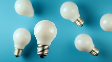 Group of white light bulbs are arranged on a blue background. The bulbs are all facing the same direction, creating a sense of unity and purpose. The image conveys a feeling of brightness