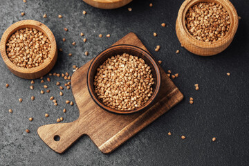 Sesame seeds arranged in wooden containers on a dark surface