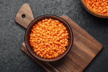 Fresh orange lentils in a wooden bowl on a rustic cutting board