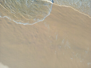 Aerial view of soft waves lapping the sandy beach