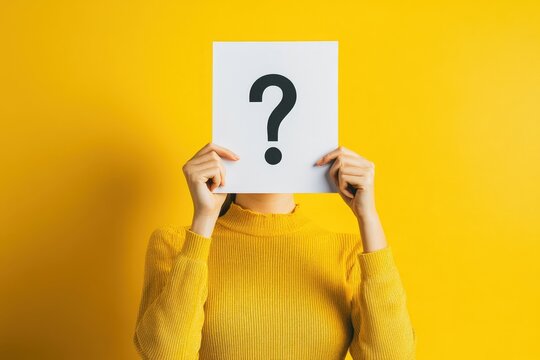 A woman holds a paper with a question mark in front of her face