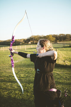 Teen age girl archer holding bow and arrow, training