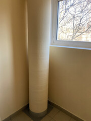 Large diameter pipe in the entrance of an apartment building runs through all floors. A garbage...