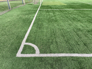 Obraz premium Artificial green grass, football field surface. Corner kick marking lines. Public soccer field.