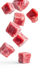 Close up view of multiple red beef cubes falling against a white background. The cubes appear slightly frozen, with a subtle icy texture.