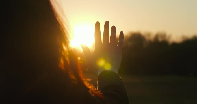silhouette woman practicing mindfulness at sunset, her hand reaching out to capture the sun s rays. mindfulness scene represents awareness, calm, and meditation in peaceful nature.