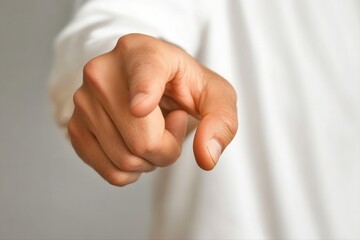 Close-up of a hand pointing assertively, against a neutral background, conveying authority