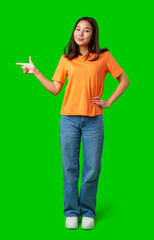 Young woman in orange shirt gestures confidently against a bright green background during a...