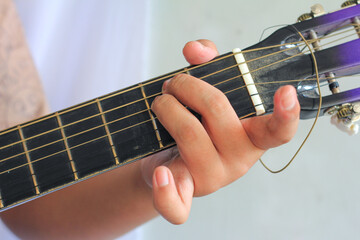 A hand pressing strings on a guitar fretboard, showcasing finger placement and technique in detail. E Minor chord