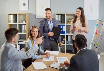 Business coach, female speaker gives flipchart presentation, speaker presenter consulting, training, persuading employees client group, young mentor leader explains strategy at team meeting workshop