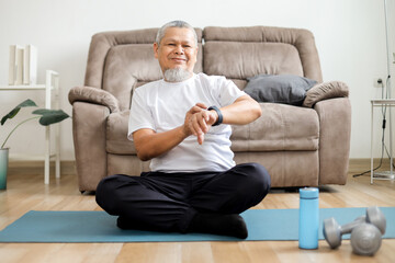 Fototapeta premium Asian Old Man in Sportswear Checking Smartwatch for Heart Rate Tracker App.