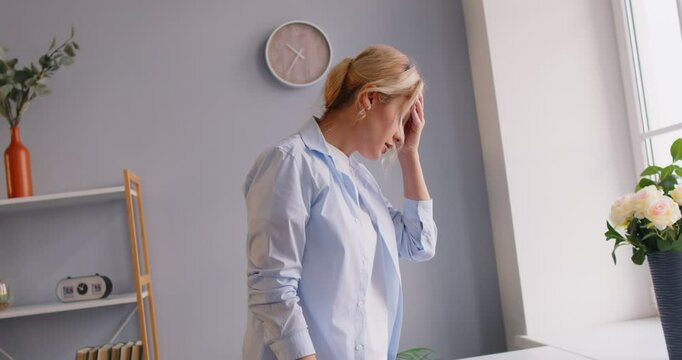 Unwell woman experiencing dizziness, headache, or migraine at home, feeling sick and fainting due to health problems. Challenges of dealing with pain and the need for medical attention.